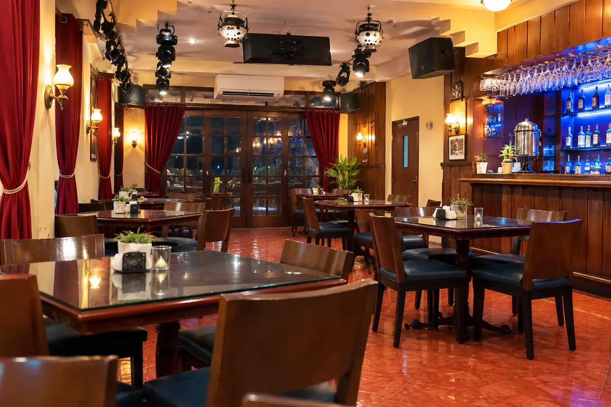 Jakarta dining room at night, tables set beside the bar and red curtains